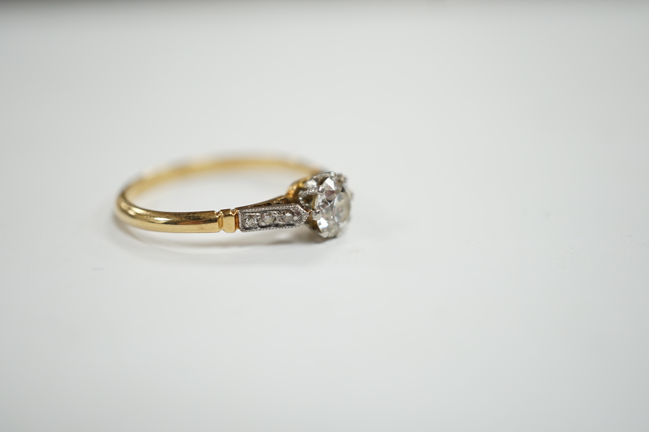 An early 20th century yellow metal and single stone diamond set ring, with diamond chip set shoulders, size N/O, gross weight 2.4 grams.